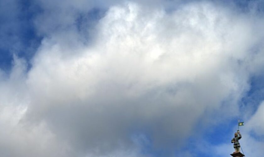 Wolken ziehen über die Statue auf dem Haus zum breiten Herd am Fischmarkt. Foto: Martin Schutt/dpa/Symbolbild