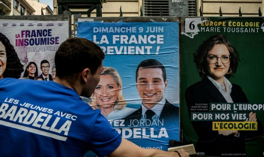 Un bénévole du RN colle une affiche de campagne de Jordan Bardella, président du parti et tête de liste aux européennes, le 6 mai 2024 à Lyon