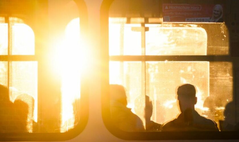 Fahrgäste sitzen bei Sonnenaufgang in einer Stadtbahn. Foto: Julian Stratenschulte/dpa/Symbolbild