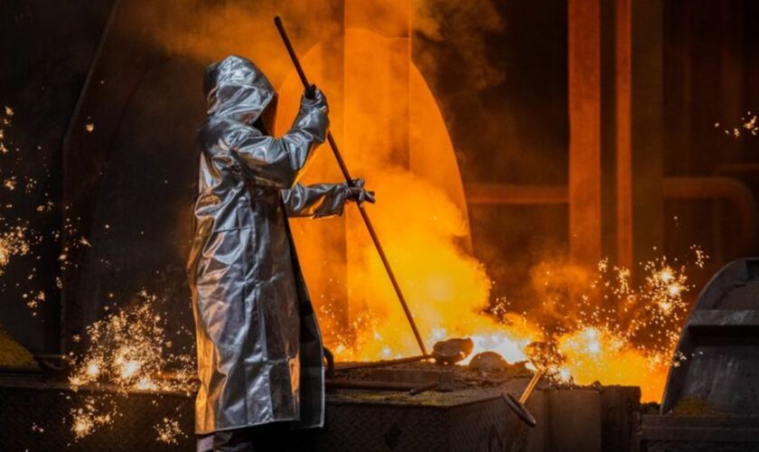 Ein Stahlarbeiter von Thyssenkrupp prüft den Roheisen am Hochofen 8 auf dem Werksgelände. Foto: Rolf Vennenbernd/dpa