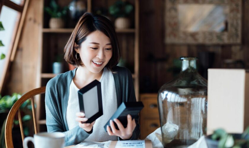 Samsung-Smartphone - Frau packt mit glücklichem Gesicht ein Packet aus.