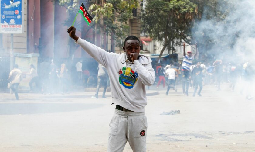 A man holds up a flag of Kenya as police use teargas to disperse protesters during a demonstration over police killings of people protesting against the imposition of tax hikes by the government in Nairobi, Kenya, July 2, 2024. REUTERS/Monicah Mwangi