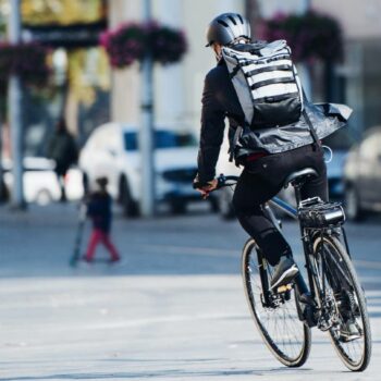 Rolltop-Rucksack: Mann mit Rolltop-Rucksack auf dem Fahrrad