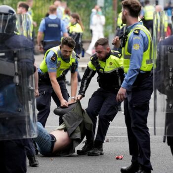 Officers detain a protester after violence at the former site of the Crown Paints factory in Coolock, north Dublin. Pic: PA