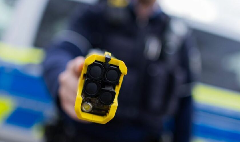 Ein Polizist hält einen Taser (Distanzelektroimpulsgerät) in den Händen. (Archivfoto) Foto: Rolf Vennenbernd/dpa