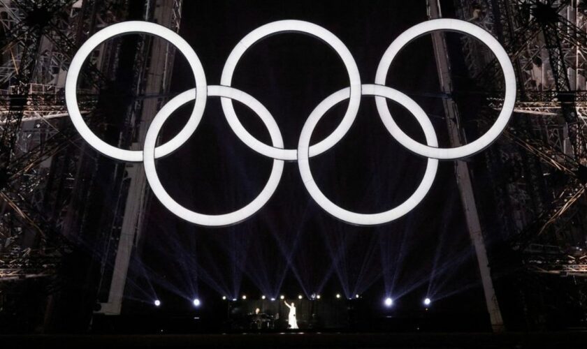 Céline Dion auf dem Eiffelturm unter den olympischen Ringen.