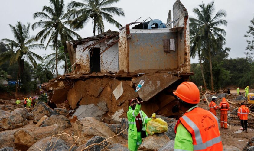 A volunteer throws a bottle of water to a man during rescue operations after several landslides hit the hills in Wayanad district, in the southern state of Kerala, India, July 31, 2024. REUTERS/Francis Mascarenhas