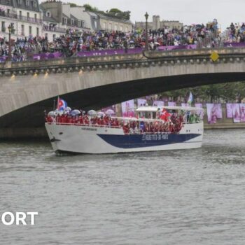 Athletes sail in a boat along the river Seine as rain starts at the start of the opening ceremony of the Paris 2024 Olympic Games in Paris