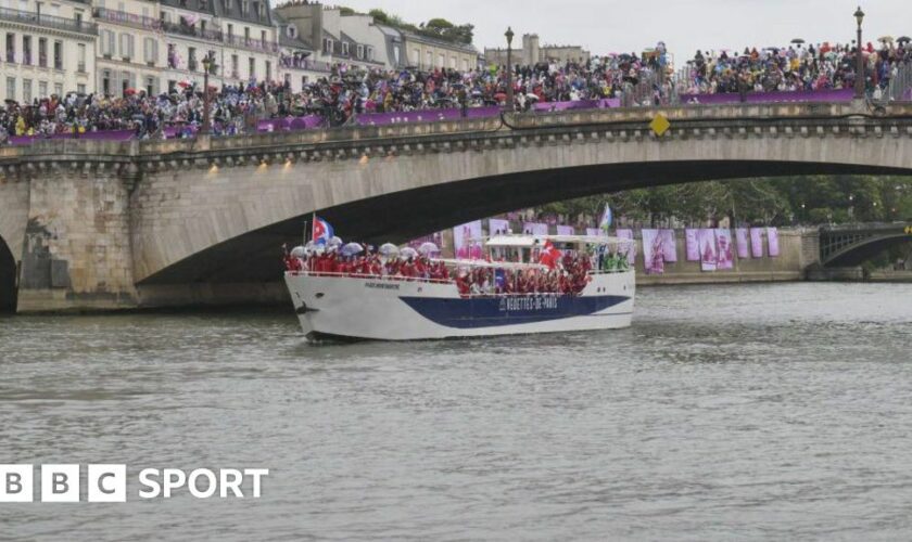 Athletes sail in a boat along the river Seine as rain starts at the start of the opening ceremony of the Paris 2024 Olympic Games in Paris