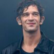 Matty Healy, Sänger der Band The 1975, steht mit Monitor-Kopfhörern auf der Bühne