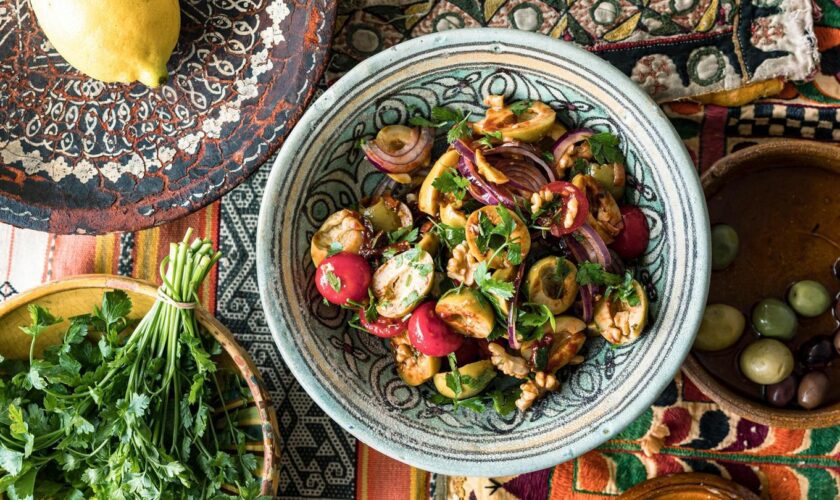 Olivensalat angerichtet neben Zitrone und Kräutern