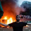 A man holding a Bangladesh flag stands in front of a vehicle that was set on fire at the Ganabhaban, the Prime Minister's residence, after the resignation of PM Sheikh Hasina in Dhaka, Bangladesh, August 5, 2024. REUTERS/Mohammad Ponir Hossain TPX IMAGES OF THE DAY