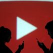 Silhouettes of mobile users are seen next to a screen projection of Youtube logo in this picture illustration taken March 28, 2018. REUTERS/Dado Ruvic/Illustration