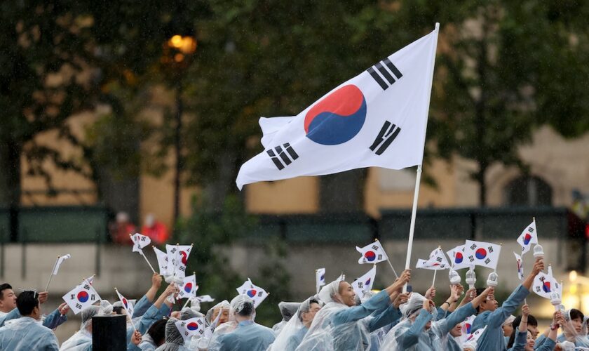 Seoyeong Kim et Sanghyeok Woo, porte-drapeaux de l'équipe de la République de Corée, sont vus en train d'agiter leur drapeau le long de la Seine lors de la cérémonie d'ouverture des Jeux Olympiques Paris 2024, le 26 juillet 2024 à Paris, France.