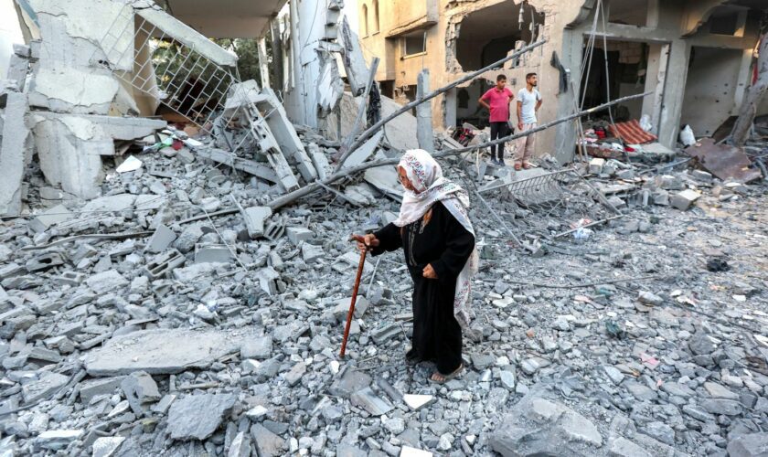 A Palestinian woman walks past destroyed houses at the site of an Israeli strike, amid the Israel-Hamas conflict, in Deir Al-Balah in the central Gaza Strip, August 7, 2024. REUTERS/Ramadan Abed.