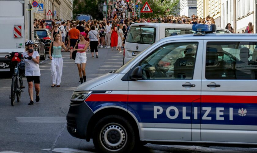 Ein Polizeiauto steht in der Nähe von versammelten "Swifties" in Wien