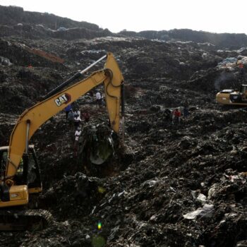 Onlookers watch as workers search for survivors at the site of a collapsed landfill in Kampala, Uganda, Sunday, Aug. 11, 2024. (AP Photo/Hajarah Nalwadda)