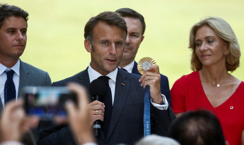 Le président de la République Emmanuel Macron, au centre, tient une médaille d'or des Jeux de Paris 2024, le 12 août 2024, à Paris