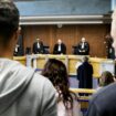 Des membres du public et des avocats se tiennent debout pendant que les juges entrent dans une salle d'audience avant une audience de procès au palais de justice de Bobigny, dans la banlieue nord-est de Paris, le 15 janvier 2024.