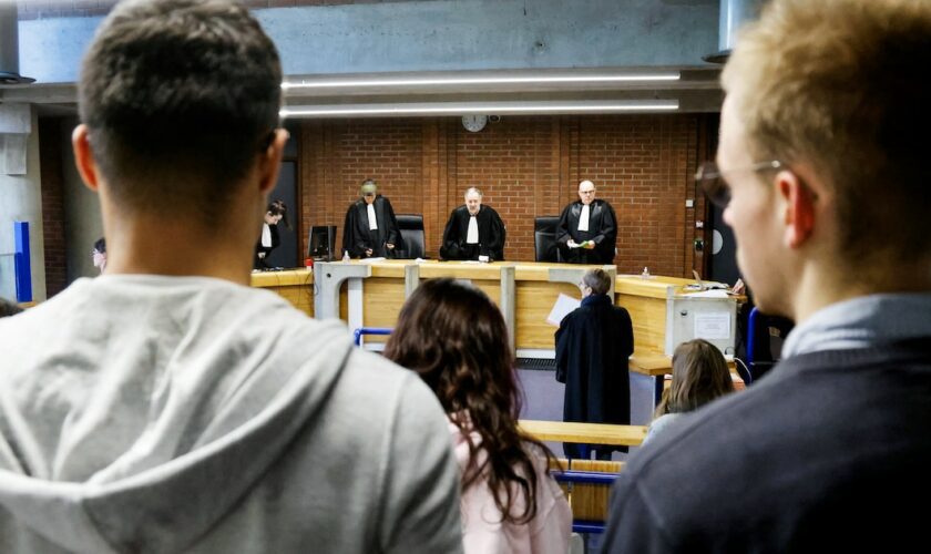 Des membres du public et des avocats se tiennent debout pendant que les juges entrent dans une salle d'audience avant une audience de procès au palais de justice de Bobigny, dans la banlieue nord-est de Paris, le 15 janvier 2024.