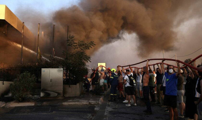 Volunteers and firefighters try to extinguish a fire in a building as a wildfire burns in Vrilissia near Athens, Greece, August 12, 2024. REUTERS/Alexandros Avramidis