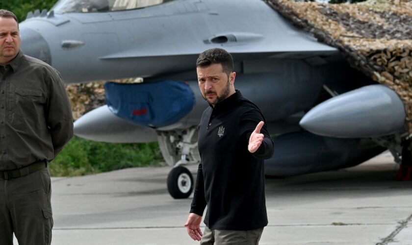 Le président ukrainien Volodymyr Zelensky (D) devant un chasseur F-16 lors d'une cérémonie dans un lieu tenu secret en Ukraine, le 4 août 2024