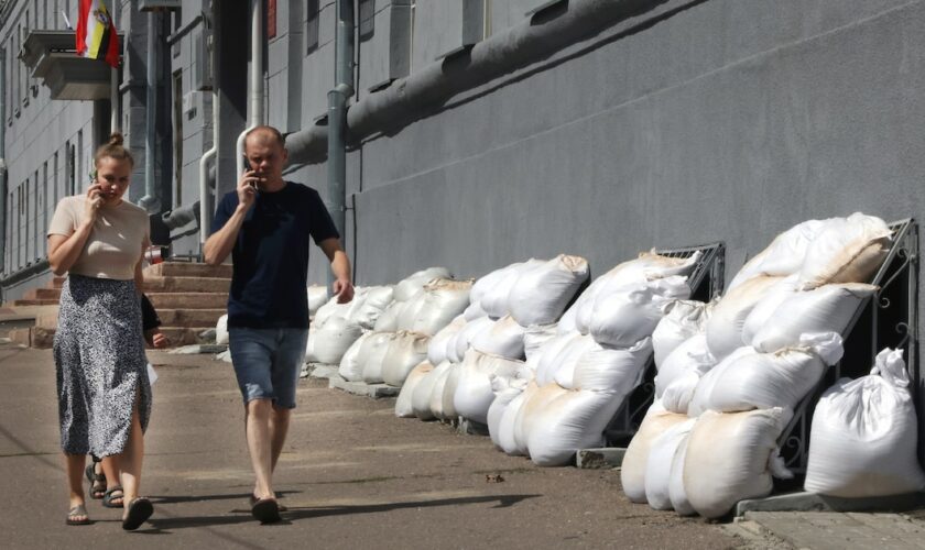 Des habitants passent devant la mairie dont les fenêtres du sous-sol sont protégées par des sacs de sable, à Koursk, le 16 août 2024 en Russie