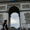 Des policiers passent devant l'Arc de triomphe arborant le sigle des Jeux paralympiques de Paris, le 22 juillet 2024