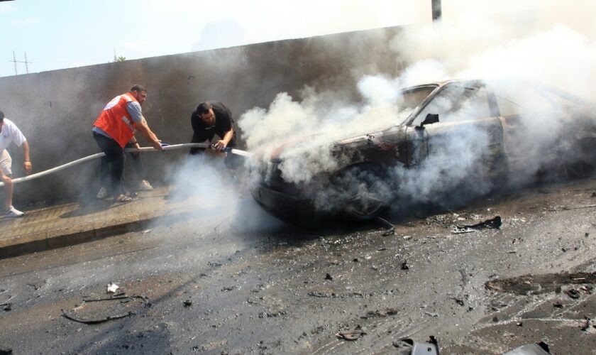 Des pompiers libanais éteignent le feu dans une voiture après une attaque israélienne à Saïda, dans le sud du Liban, le 21 août 2024, qui a tué un responsable de la branche armée du Fatah palestinien