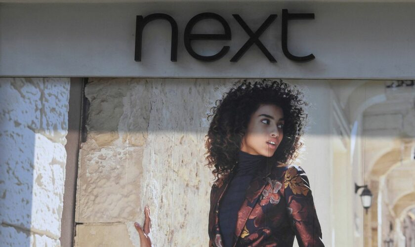 FILE PHOTO: Shoppers pass a branch of Next retail in London, Britain, September 15, 2016. REUTERS/Toby Melville/File Photo