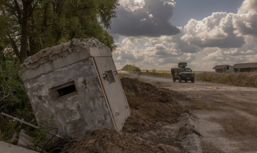 Un véhicule militaire blindé ukrainien passe devant un poste-frontière détruit avec la Russie, dans la région de Soumy, le 14 août 2024