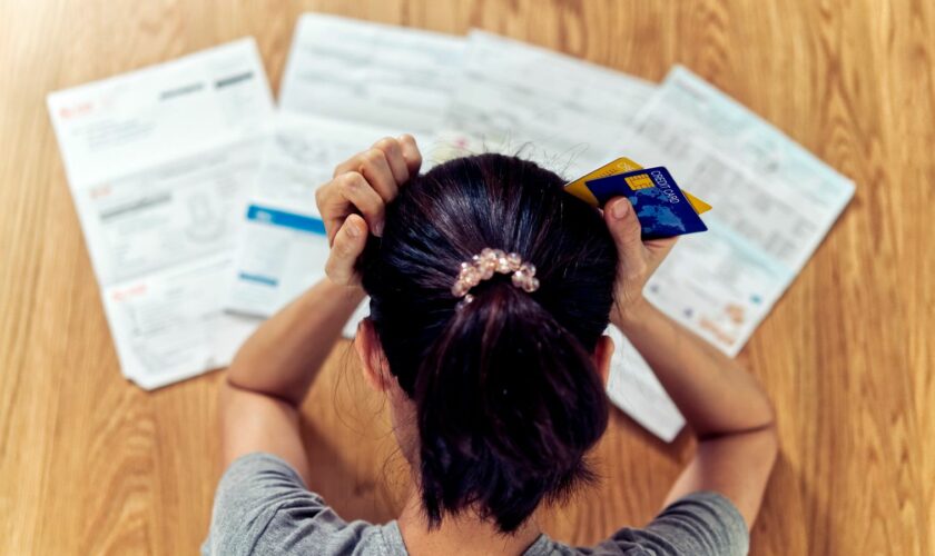 Top view of stressed young sitting Asian woman hands holding the head worry about find money to pay credit card debt and all loan bills. Financial problem concept. (GDA via AP Images)