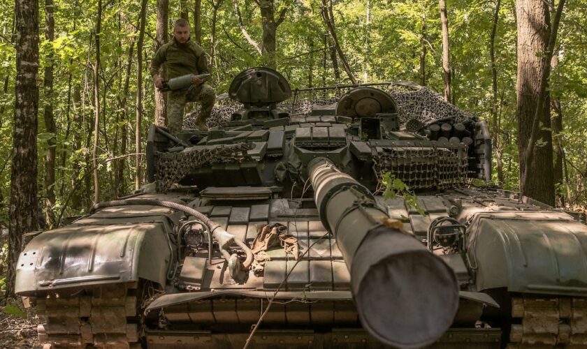 Un militaire ukrainien porte un obus d'un char T-72 de fabrication soviétique, dans la région de Soumy, près de la frontière avec la Russie, le 12 août 2024