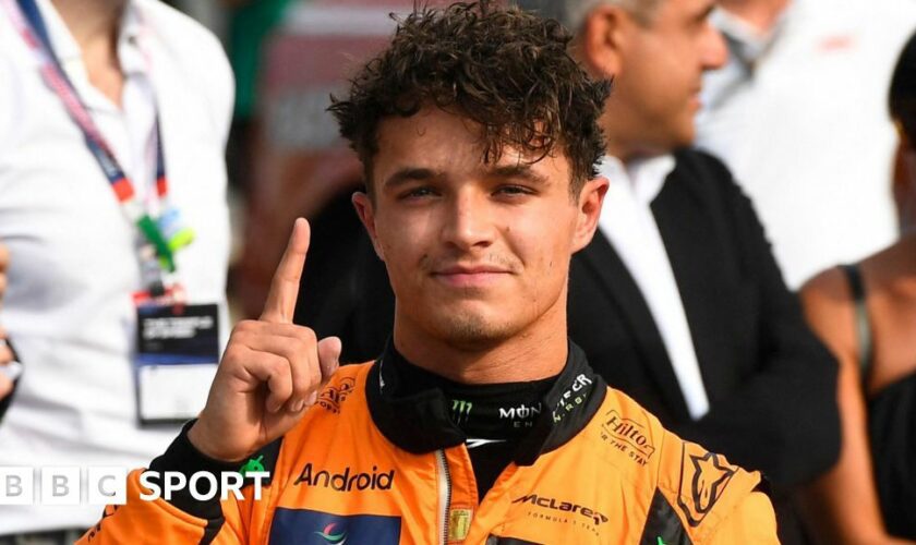 Lando Norris puts up a finger to denote his pole position