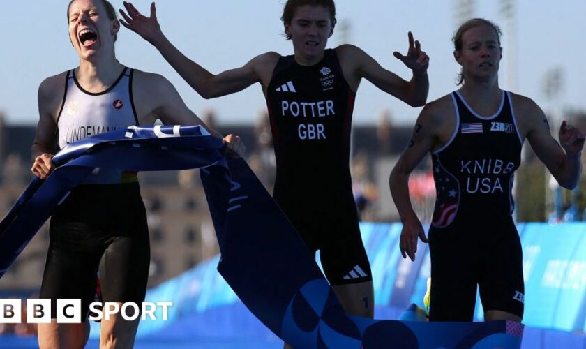 Alex Yee, Georgia Taylor-Brown, Beth Potter and Sam Dickinson pose with a Great Britain flag after winning bronze in the mixed relay triathlon at the Paris 2024 Olympics