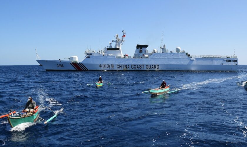 Des pêcheurs philippains devant un navire militaire chinois au large du récif de Scraborough, un îlot contrôlé par la Chine mais revendiqué par les Philippines, le 15 février 2024