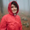 Eine Frau trägt einen Regenponcho im Wald