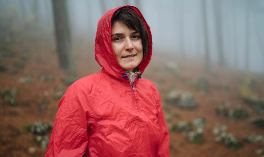 Eine Frau trägt einen Regenponcho im Wald