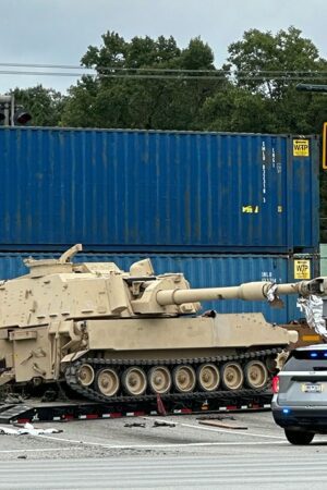 Train collides with military mobile artillery vehicle being hauled on a semi-truck