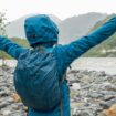 Wasserdichter Rucksack: Frau steht in Regenjacke und mit Rucksack an einem Fluss