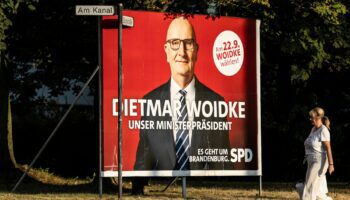 Eine Frau spaziert an einer großen Wahlplakatwand der SPD zur Brandenburg-Wahl mit Dietmar Woidke vorbei