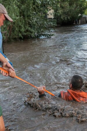 Rescuers pull a man through flooded water and to safety in Romania amid the ongoing floods. Pic: Reuters