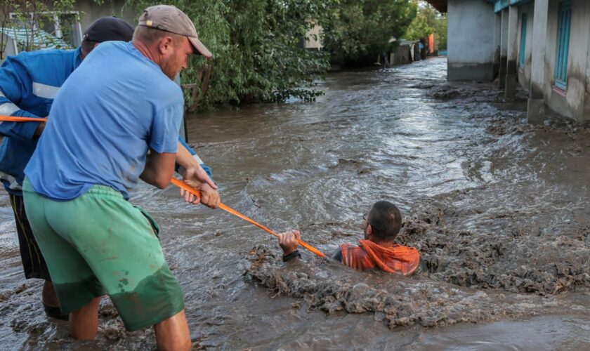 Rescuers pull a man through flooded water and to safety in Romania amid the ongoing floods. Pic: Reuters