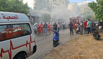 People gather as smoke rises from a mobile shop in Sidon, Lebanon September 18, 2024. REUTERS/Hassan Hankir