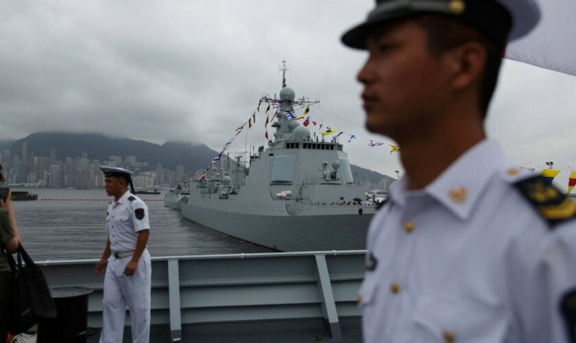 Des marins chinois à bord du Yinchuan, un destroyer de type 052D de la marine de l'Armée populaire de libération (APL), surveillent les visiteurs tandis que le destroyer de type 052C de la marine de l'APL Jinan (C, arrière-plan) est exposé au public à la base navale de Ngong Shuen Chau à Stonecutters.