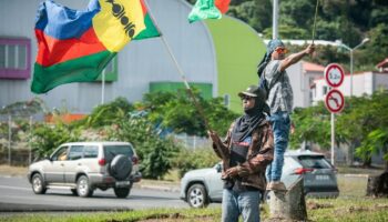 Des partisans de l'indépendance de la Nouvelle-Calédonie agitent des drapeaux sur le bord d'une route aà Nouméa, le 27 juin 2024