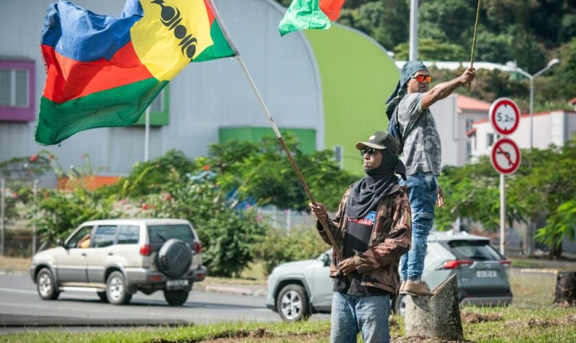 Des partisans de l'indépendance de la Nouvelle-Calédonie agitent des drapeaux sur le bord d'une route aà Nouméa, le 27 juin 2024