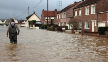 Un homme marche le 3 janvier 2024 dans une rue inondée d'Arques, dans le nord de la France, suite à la crue de l'Aa