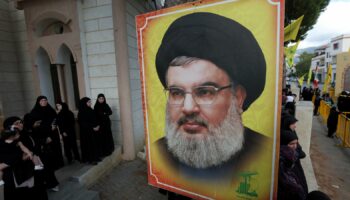 People stand near a picture of Hezbollah leader Sayyed Hassan Nasrallah during the funeral of Hezbollah member Ali Mohamed Chalbi, after hand-held radios and pagers used by Hezbollah detonated across Lebanon, in Kfar Melki, Lebanon September 19, 2024. REUTERS/Aziz Taher