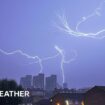 Fork lightning fills the darkened sky with some lightning hitting high rise buildings in the distance